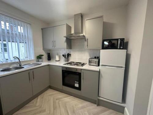 uma cozinha com armários brancos e um frigorífico branco em Hambledon- 2Bed downstairs flat Blyth em Blythe