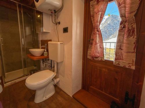 uma casa de banho com um WC e uma janela em La casetta em Prali