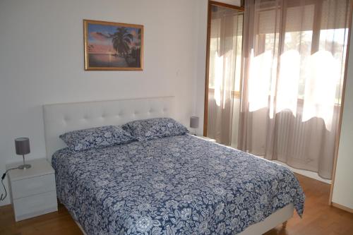 ein Schlafzimmer mit einem Bett mit blauer Decke und einem Fenster in der Unterkunft Appartamento Il Volo in Lippo di Calderara di Reno