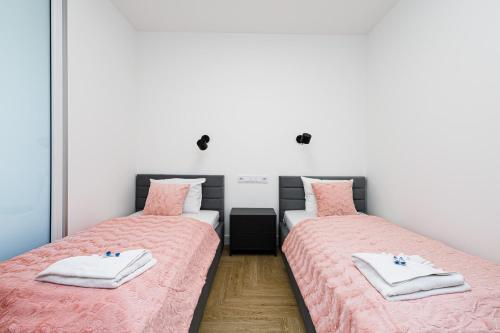 two beds in a room with pink sheets at Balticus Apartamenty Deluxe Promenada Gwiazd 14 in Międzyzdroje