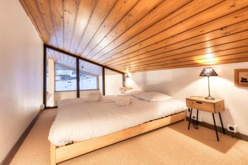 una camera da letto con un letto grande con soffitto in legno di Le Contemporain - Chalet vue sur le Mont Blanc a Saint-Gervais-les-Bains