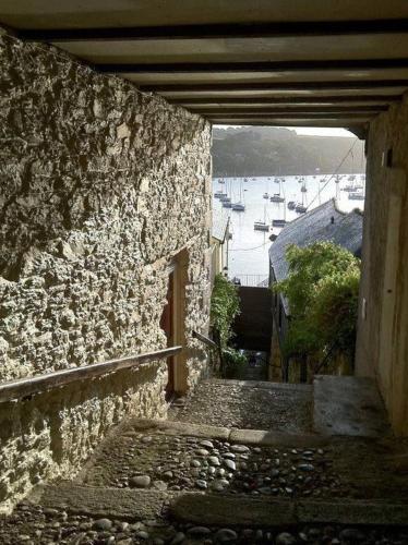 an alley way with a stone building and boats in the water at 4 Bedroom Cottage with panoramic Harbour views in Falmouth