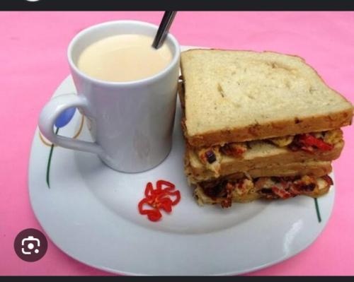 ein Sandwich auf einem Teller neben einer Tasse Kaffee in der Unterkunft Belmorris Hotel in Ilorin