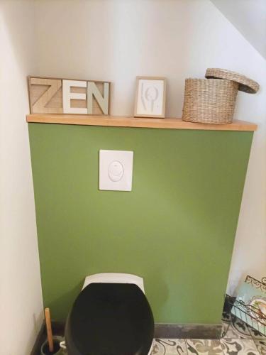 a bathroom with a green wall and a black toilet at Havre de Paix 40 in Pouillon