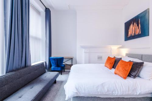 a bedroom with a white bed and a blue chair at Guestz The Old Embassy Apartments in Hull