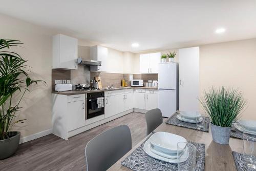 a kitchen with white cabinets and a table and chairs at Cosy Modern Studios at Sheffield 3 located near the University of Sheffield in Sheffield
