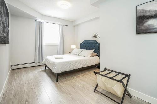 a white bedroom with a bed and a window at New Cozy 2 Bedrooms Condo w Parking in Calgary