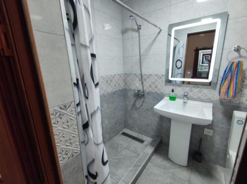 y baño con ducha, lavabo y espejo. en Квартиры посуточно и помесячно в городе Гюмри, Армения en Gyumri