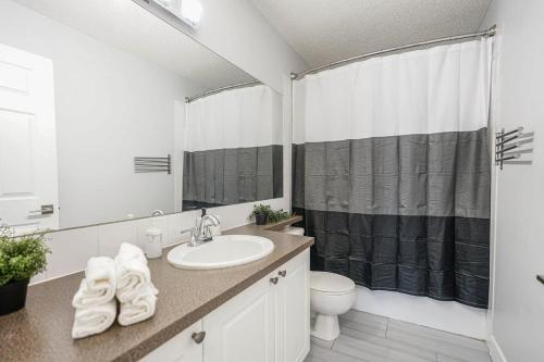 y baño con lavabo, aseo y ducha. en New Cozy 2 Bedrooms Condo w Parking en Calgary