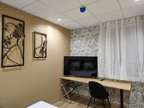 a room with a desk and a television and a window at Hôtel L'Européen in Tarbes