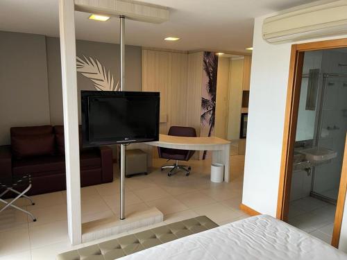 uma sala de estar com televisão e uma mesa num quarto em Quarto 50m2 próximo shopping Salvador em Salvador