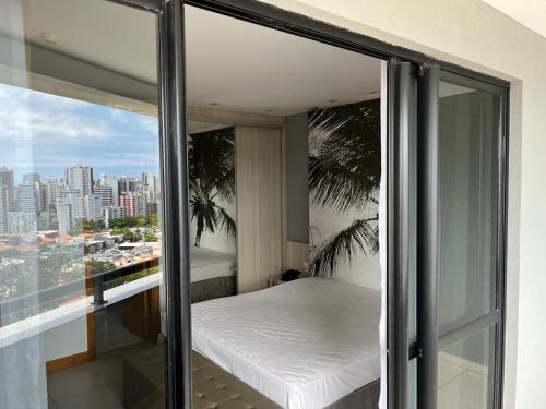 a balcony with a bed and a view of a city at Quarto 50m2 próximo shopping Salvador in Salvador