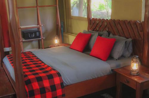 a bedroom with a bed with two red pillows at Drunken Elephant Mara in Sekenani