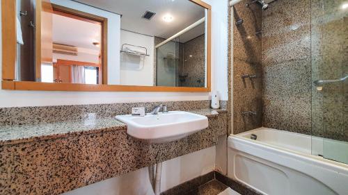 y baño con lavabo, espejo y bañera. en Flat em Hotel 4 estrelas - Alameda Lorena, en São Paulo