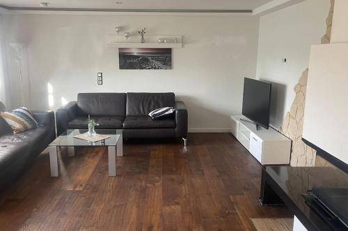 uma sala de estar com um sofá preto e uma televisão em Gästehaus Brunswiek Erdgeschoss em Vordorf