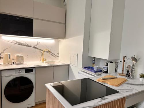 une cuisine blanche avec un évier et un lave-vaisselle dans l'établissement Beautiful, modern 1-bed apartment, 5 mins RER A, à Saint-Germain-en-Laye