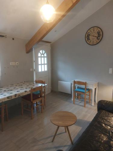 - un salon avec une table, des chaises et une horloge dans l'établissement L'Orangerie, à Idron