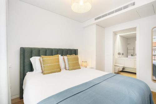 - une chambre blanche avec un grand lit et des oreillers jaunes dans l'établissement WHome Urban Oasis: Modern Living with Parking & AC, à Lisbonne