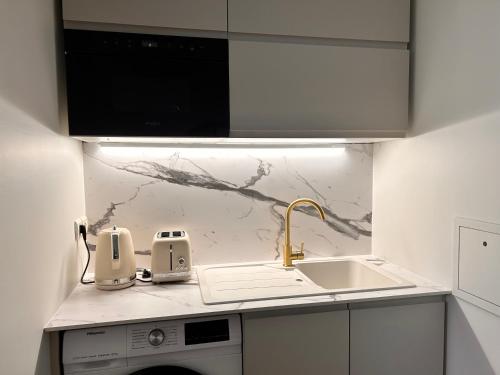 cocina blanca con fregadero y fregadero en Beautiful, modern 1-bed apartment, 5 mins RER A, en Saint-Germain-en-Laye