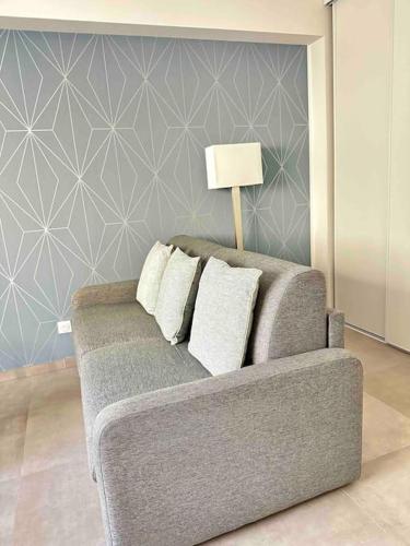 - un canapé gris avec des oreillers dans le salon dans l'établissement Bertaina - Studio cosy Gare - Libération, à Nice