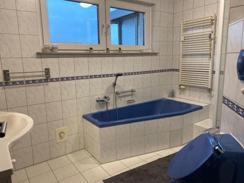 bagno con vasca blu e lavandino di Gästehaus Brunswiek Erdgeschoss a Vordorf