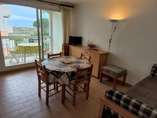 ein Wohnzimmer mit einem Tisch und Stühlen sowie einem Balkon in der Unterkunft St Cyprien terrasse superbe vue sur la plage in Saint-Cyprien