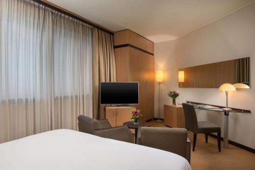 a hotel room with a bed and a desk at NH Bologna Villanova in Villanova