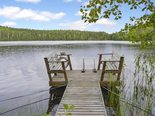 two benches sitting on a dock on a lake at Holiday Home Villa käpytikka by Interhome in Ylämylly