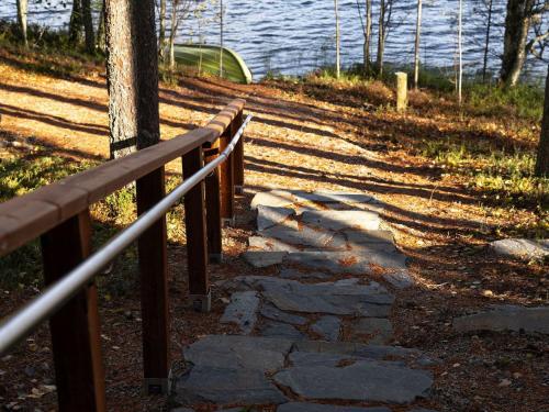 un chemin en pierre à côté d'une clôture et de l'eau dans l'établissement Holiday Home Villa käpytikka by Interhome, à Ylämylly