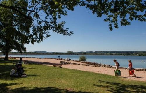 Un groupe de personnes assises sur l'herbe près d'une plage dans l'établissement Camping du Lac, à Villegusien Le Lac