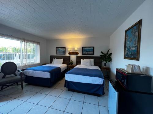 una camera d'albergo con due letti e una televisione di Nocturne Motel a New Smyrna Beach