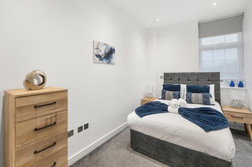a bedroom with a bed and a wooden dresser at Welcoming and Spacious Apartment- Excellent Location in London