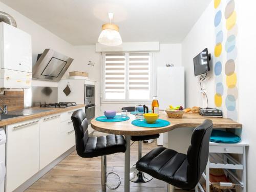 une cuisine avec une table en bois et des chaises noires dans l'établissement Apartment Le chant des mouettes by Interhome, à Saint-Malo