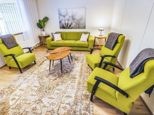 salon z zielonymi krzesłami i stołem w obiekcie Holiday Home Mäntyranta 4 by Interhome w mieście Punkaharju