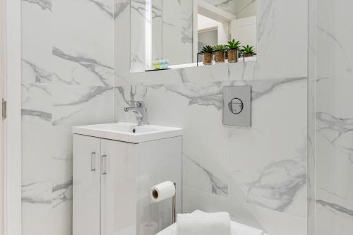biała łazienka z umywalką i prysznicem w obiekcie Welcoming and Spacious Apartment- Excellent Location w Londynie