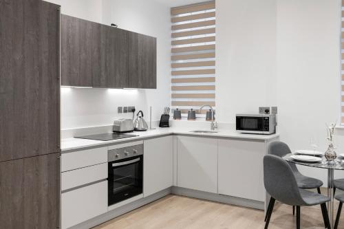 a kitchen with white cabinets and a table with chairs at Welcoming and Spacious Apartment- Excellent Location in London