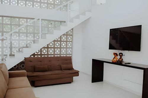 a living room with a couch and a tv and stairs at Familia Pansini casa na Pipa in Pipa