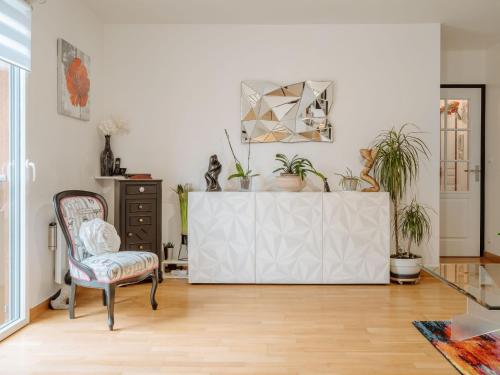 a living room with a chair and potted plants at Apartment Les Rives de la Rance by Interhome in La Richardais