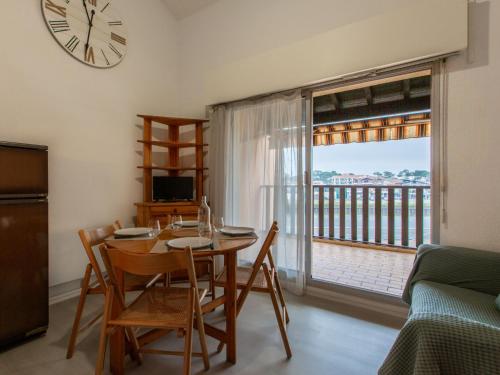 une salle à manger avec une table, des chaises et une horloge dans l'établissement Apartment Les Terrasses Notre Dame du Port-9 by Interhome, à Capbreton