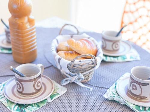 une table avec trois tasses et un panier de pâtisseries dans l'établissement Apartment Les Jardins de la Plage-12 by Interhome, à Canet