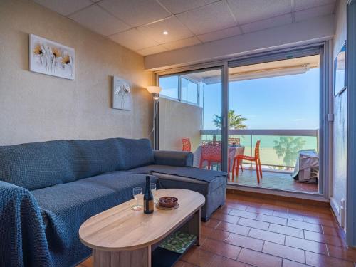 un salon avec un canapé bleu et une table dans l'établissement Apartment Les Jardins de la Plage-12 by Interhome, à Canet