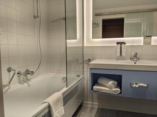 La salle de bains est pourvue d'une baignoire, d'un lavabo et d'une douche. dans l'établissement Hotel an der Therme, à Bad Orb
