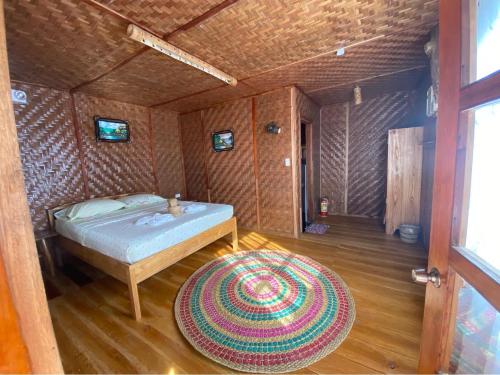 a bedroom with a bed and a rug in a room at Hola Beach Resort in Siquijor