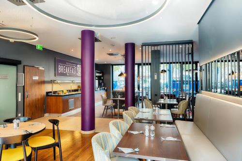 un restaurante con columnas púrpuras, mesas y sillas en Premier Inn Frankfurt City Europaviertel, en Frankfurt