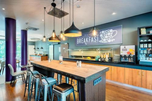 a restaurant with a large bar with stools at Premier Inn Frankfurt City Europaviertel in Frankfurt/Main