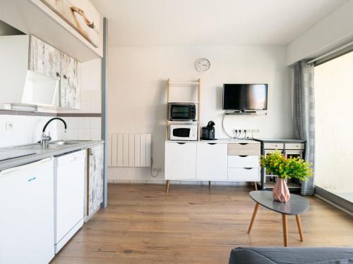 une cuisine avec des armoires blanches et une table dans l'établissement Apartment Mon oxygène by Interhome, à Mimizan