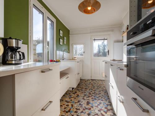 une cuisine avec des armoires blanches et un sol carrelé dans l'établissement Holiday Home L'albizia by Interhome, à Canapville