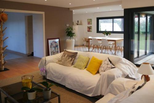 uma sala de estar com um sofá branco com almofadas amarelas em La Villa sous Les Pins em La Trinité-sur-Mer