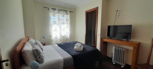 um quarto com uma cama e uma televisão de ecrã plano em Guesthouse, Ap Veríssimo na Nazaré