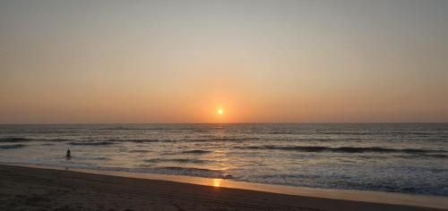 eine Person, die am Strand steht und den Sonnenuntergang beobachtet in der Unterkunft HospedajesPerú in Zorritos